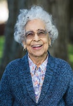Mildred Hernandez is pictured in a midrange photograph. She is smiling broadly and has curly gray hair. 