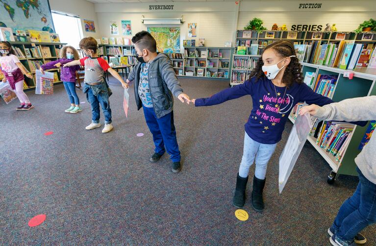 children line up, spreading their arms out and touching fingertip to fingertip