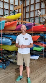 Cody James Pace stands in front of a group of kayaks at The Paddle Shack in Scappoose, Ore. in October 2025.