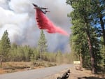 In this photo provided by the Bootleg Fire Incident Command, a plane drops retardant near Mitchell Monument in the Bootleg Fire, July 19, 2021.