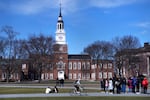 A bicyclist passes a college tour group outside the Baker Library at Dartmouth College, April 7, 2023, in Hanover, N.H.