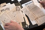 Henry Groepper, chairman of Crime Stoppers of Oregon, shuffles through newspaper clippings featuring unsolved crimes and cases he has collected over the years at his home in Portland, Ore. on Sept. 18, 2026.
