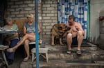 Elena Dyachkova (center) and Aleksander Dokalenko (right), and their dog, Lord, share a dinner with their neighbor, Valentina (left), at their house in Avdiivka in July 2018.
