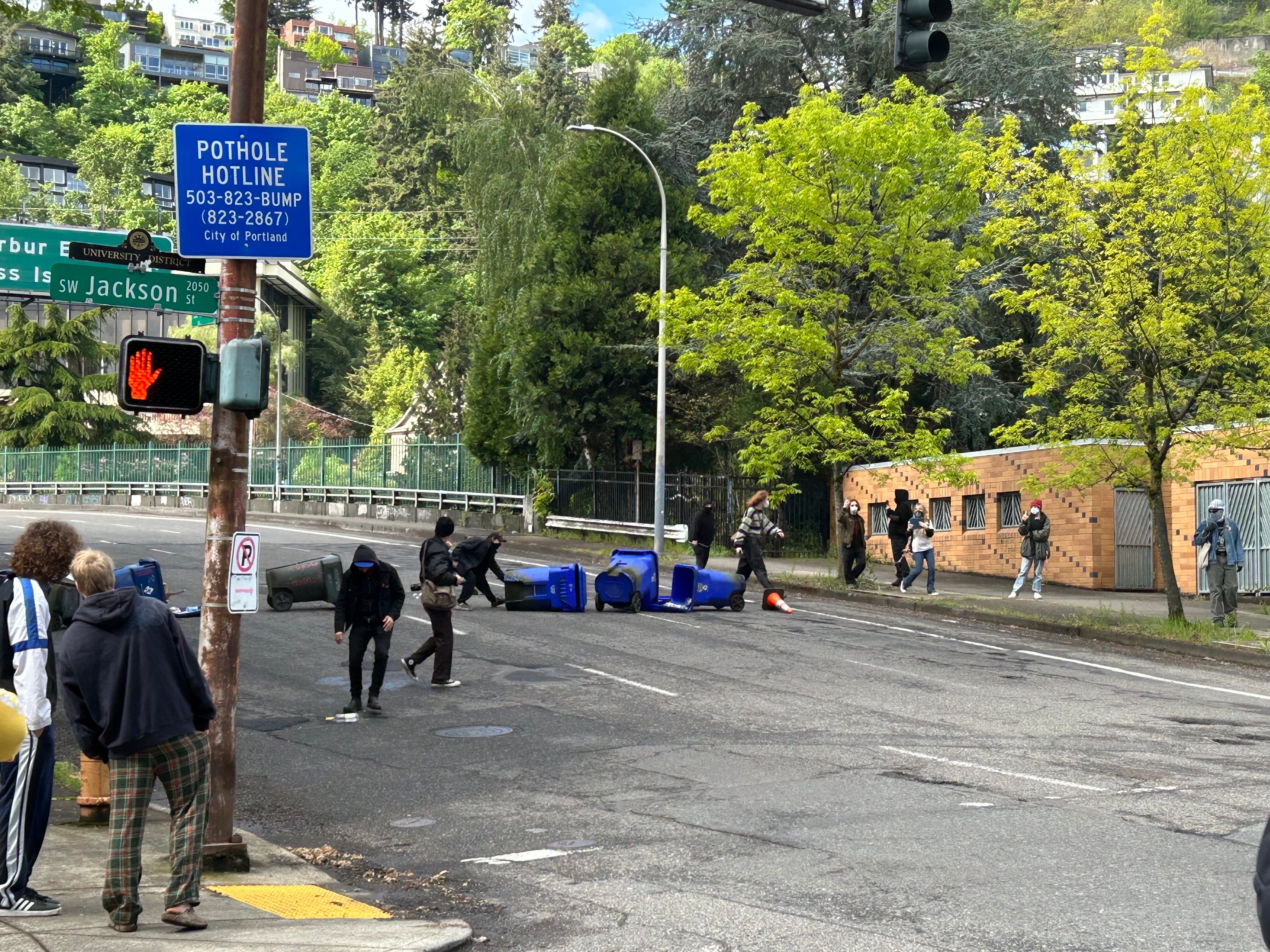 Protesters place recycling bins on a street to block traffic near the Portland State University campus on Thursday, May 2, 2024.