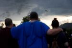 Mourners gather during a vigil for victims of the Impact Plastics tragedy, while a helicopter continues search and rescue work, in Erwin, Tenn. on Oct. 3.