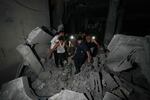 Palestinians carry the body of a person who was found under the rubble of a destroyed mosque following an Israeli airstrike in Deir al-Balah, Sunday.