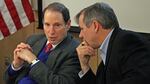Senators Ron Wyden and Jeff Merkley wear suits and talk to one another.