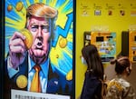 People walk past a cryptocurrency exchange office with a screen featuring President Donald Trump holding cryptocurrency coins in Hong Kong on March 12, 2025.