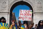 People holds a sign during a rally against Russia's invasion of Ukraine at Washington Square Park in New York, Sunday, Feb. 27, 2022.