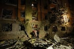 Rescue workers walk in front of a residential building damaged by a Russian airstrike in Zaporizhzhia, Ukraine, on Saturday.