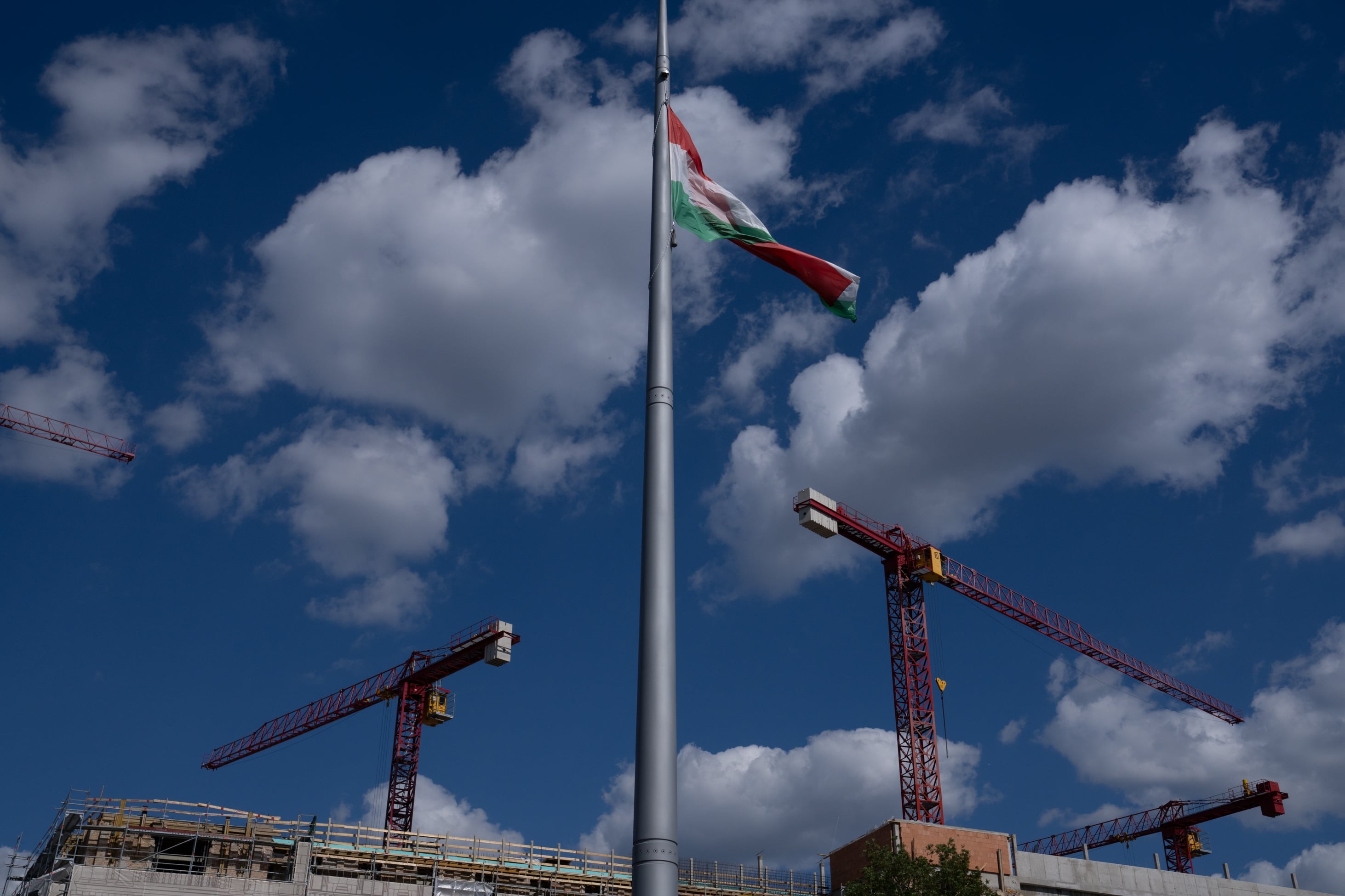 Construction cranes can be seen in Budapest's castle district, along with the Hungarian flag.