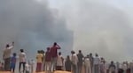 People watch smoke rising after an airplane crashed in Ahmedabad, Gujarat state, India, on Thursday.