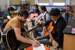 Wilson Vediner, left, teaches a student chords on the guitar at the Pass the Mic workshop at Hosford Middle School in Portland, Ore., Monday, July 29, 2019. Vediner, who's played in bands like Months and Point Juncture, WA, is the workshop's program director.