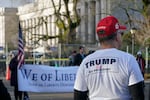 A supporter of President Donald Trump listens to speakers during a rally, Sunday, Jan. 10, 2021, at the Capitol in Olympia, Wash. Protesters from several causes rallied Sunday at the Capitol, which was secured with a perimeter fence and National Guard members, the day before the 2021 legislative session was scheduled to begin.
