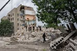 Rescue workers stand on the rubble at the scene of a missile strike that hit a residential apartment block in Chasiv Yar, which is located in Ukraine's Donetsk region. The strike took place Saturday night and left at least 15 people dead.