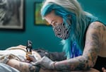 Olivia Britz-Wheat tattoos a customer at her shop, Mortal Emblem, at Lloyd Center, May 11, 2023. Lloyd Center’s new owners are aiming to revive the once popular shopping destination in Northeast Portland—hosting events and bringing in more small and local retail businesses.