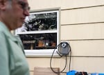 Kip Silverman stands in the driveway of his home, where he has a charging station installed.
