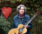 Award-winning Portland musician Mary Flower is shown in this undated, provided photo holding an acoustic guitar. Flower has been performing and teaching guitar for decades in a variety of different genres, from folk to blues and jazz. On Oct. 11, 2025, Folk Alliance Region-West is honoring her with its "Best of the West Artist Award," at its annual conference, held this year in Vancouver.