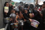 Palestinians, including children, who are struggling to access food due to Israel's blockade and ongoing attacks on the Gaza Strip, wait in line to receive food.