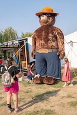 Rachel Wafford, of Prineville, photographs her children, John, 3, and Willa, 6, with a towering Smokey Bear display at the Crook County Fair. Wafford said the fair marks the end of summer for her family and that she didn't want the children to miss it.