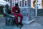 A local hip hop artist named Spazz sits on the Thomas Jefferson statue that was torn down from its pedestal at Jefferson High School in Northeast Portland