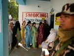 Paramilitary soldiers stand guard as people queue up to vote during the first phase of the Jammu and Kashmir assembly election, in Kishtwar, India, on Wednesday.