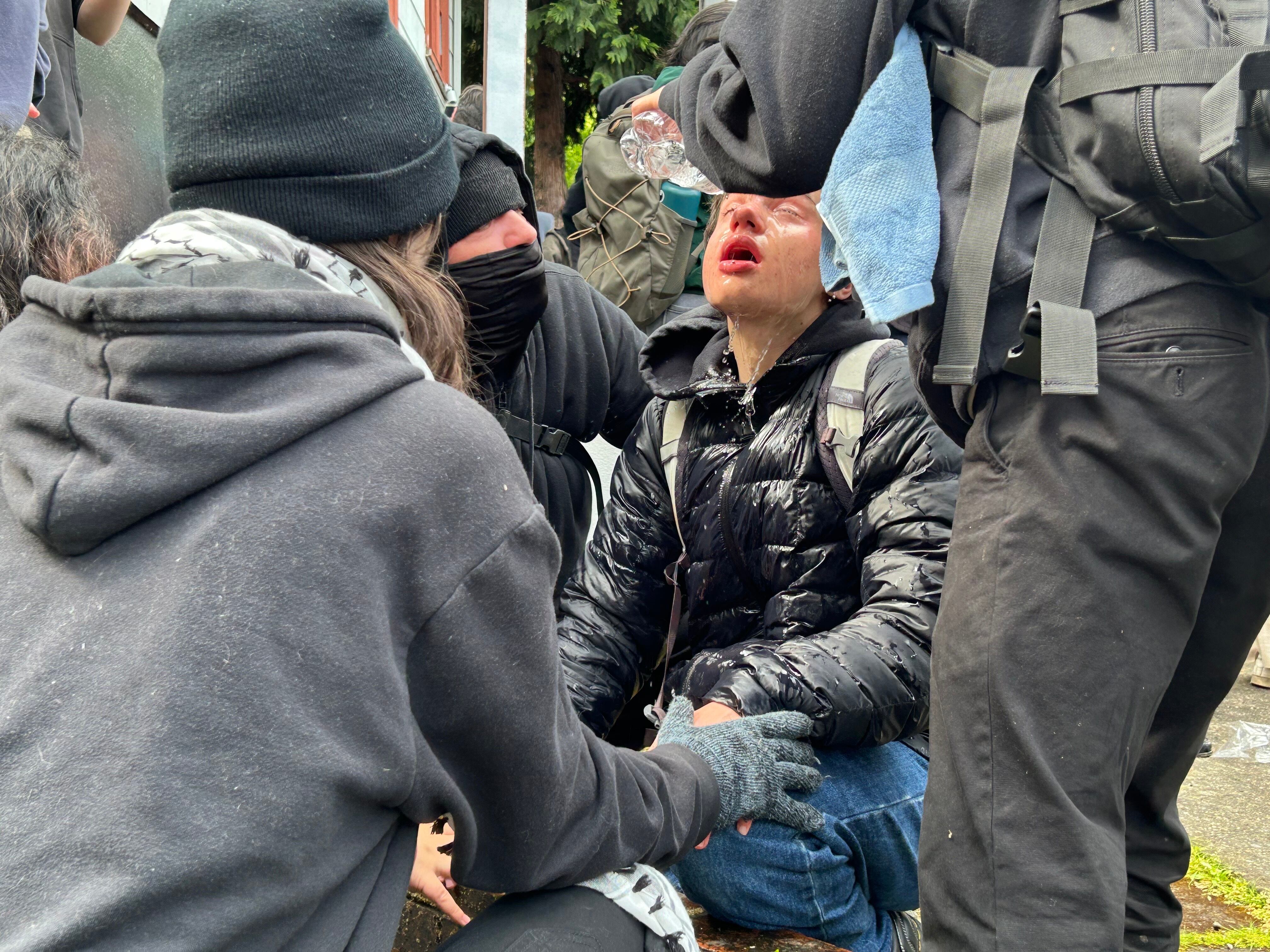 People help someone who got pepper-sprayed in the face at the Portland State University campus on Thursday, May 2, 2024. Portland police formed a perimeter early in the morning around the school's library to remove protesters US involvement in Israel's role in the ongoing war in Gaza.