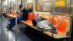 A person sleeps on the seats of a New York City subway train.