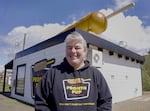 A woman with gray hair in a ponytail wears a black sweatshirt that says "Pronto Pup" outside a corn dog restaurant.