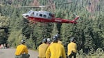 Firefighters wait to board a crew helicopter while working the Bear Gulch Fire on Washington's Olympic Peninsula in this provided image from August 2025.