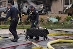 Police help rescue dogs from a home after a small plane crashed into a San Diego neighborhood earlier, setting several homes on fire and forcing evacuations along several blocks, Thursday, May 22, 2025.