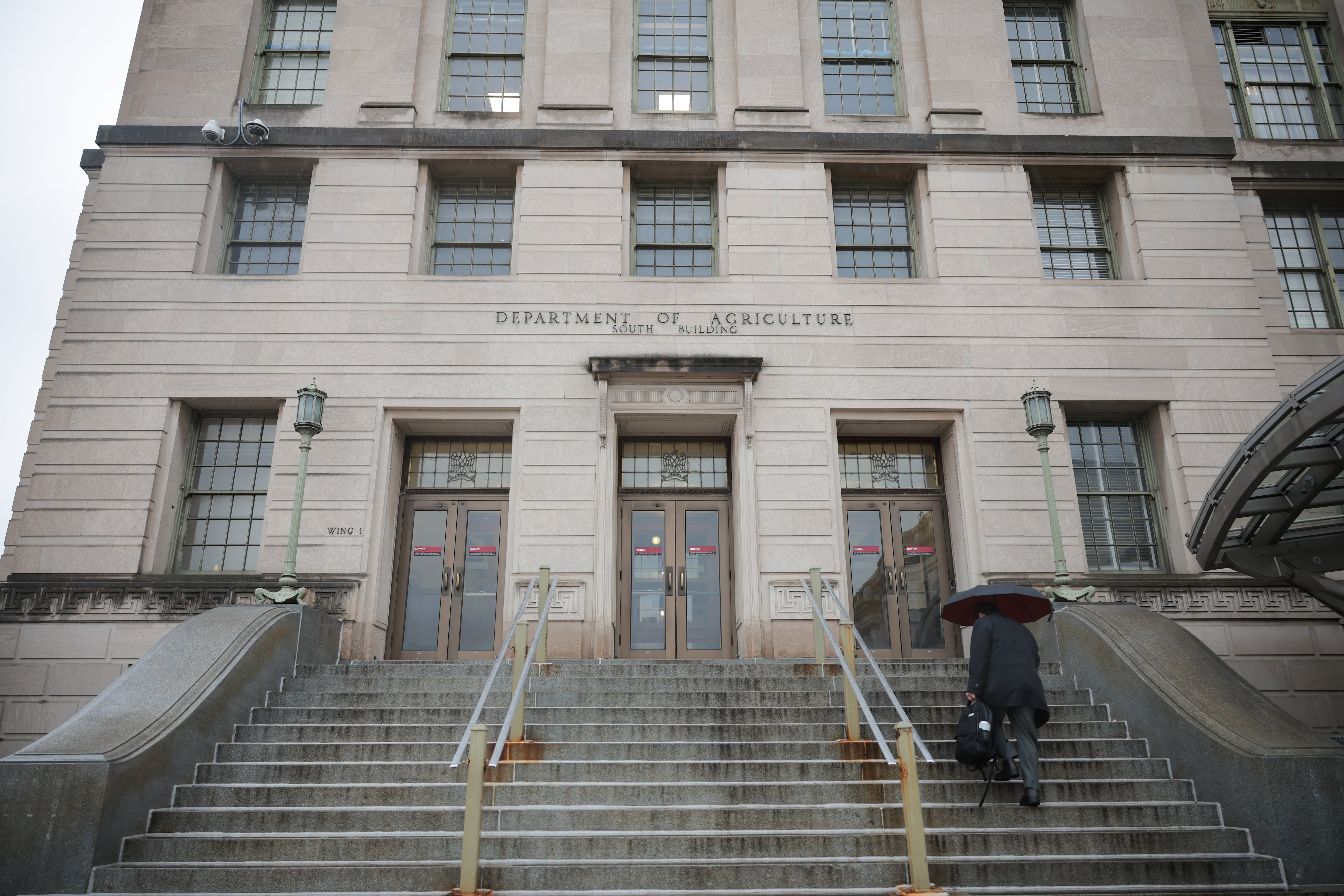 A person walks with an umbrella as rain falls on the Department of Agriculture building in Washington, D.C., on April 11.