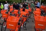 rows of orange BIKETOWN bikes are lined up in front of a crowd of people