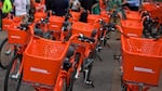 rows of orange BIKETOWN bikes are lined up in front of a crowd of people