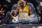 FILE - In this Jan. 26, 2021, file photo, Adam Dergazarian, bottom center, pays his respects for Kobe Bryant and his daughter, Gianna, in front of a mural painted by artist Louie Sloe Palsino in Los Angeles. Federal safety officials are expected to vote Tuesday, Feb. 9, 2021, on what likely caused the helicopter carrying Kobe Bryant, his 13-year-old daughter and seven others to crash into a Southern California hillside last year, killing all aboard.