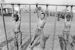 Salvadoran army recruits hang from a crossbar during a training exercise overseen by United States Army Rangers and Special Forces at the Ilopango air base in San Salvador, El Salvador, March 1983. T(Photo by Robert Nickelsberg/Getty Images)