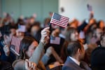 People wave U.S. flags to celebrate becoming U.S. citizens after taking the oath of allegiance during a naturalization ceremony in Boston in January 2025.