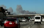 Smoke from a brush fire in the Pacific Palisades rises over the 405 freeway in Los Angeles on Tuesday.