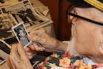 FILE - Pearl Harbor survivor Ira "Ike" Schab, 103, looks at an old photo of himself with a saxophone while sitting at the kitchen table in his home in Beaverton, Ore. on Monday, Nov. 20, 2023.