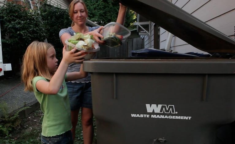 Libby Mills, 7, helps her mom Sara Mills in dumping the family’s food scraps into the yard waste container. Libby says, “It’s not very di fficult just to put something in a bin.”