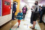 Gov. Kate Brown (center right, dark blue mask) visits  Scott Elementary School in Northeast Portland on  April 1, 2021. Arrows and lines on the floor tell students and staff how to walk down the school halls to maintain distance. 