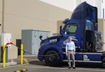 Keith Wilson, the president and CEO of Titan Freight Systems, stands next to a heavy-duty electric truck being charged at the Freightliner test facility in Chino, California in October 2021.