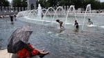 Visitors and tourists to the World War II Memorial in Washington, D.C., seek relief from the hot weather in the memorial's fountain on July 3. Due to extreme temperatures and high humidity, D.C. has declared a heat emergency, urging residents to take precautions outside and to stay hydrated.