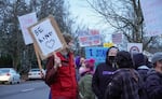 A group of people hold signs at an outside demonstration against racism.