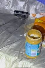 An open jar of peanut butter and a gun-mountable flashlight inside a tent.