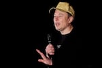 Elon Musk, dressed in black and wearing a baseball cap, wields the microphone at a town hall-style meeting in Folsom, Pa. 