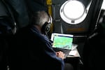 A scientist sits in the cockpit and helps coordinate a flight plan through "snow bands" in the storm.