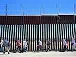 Migrants walk on the U.S. side of the border wall in Jacumba Hot Springs, Calif., on June 5, after crossing from Mexico.
