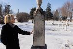 Brown County Historical Society researcher Darla Gebhard touches a grave marker at the New Ulm City Cemetery in New Ulm, Minnesota.