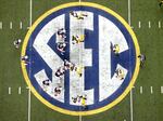 FILE - Auburn quarterback Nick Marshall (14), left, takes the snap from Auburn center Reese Dismukes (50) as the Auburn offense operates against Missouri on the SEC logo during the first half of Auburn's 59-42 win over Missouri in the SEC Championship at the Georgia Dome, Saturday, Dec. 7, 2013, in Atlanta, Ga. 
